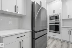 Kitchen with stainless steel appliances, white cabinetry, modern cabinets, and light wood-style floors - 