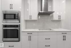 Kitchen featuring white cabinets, extractor fan, appliances with stainless steel finishes, and decorative backsplash - 
