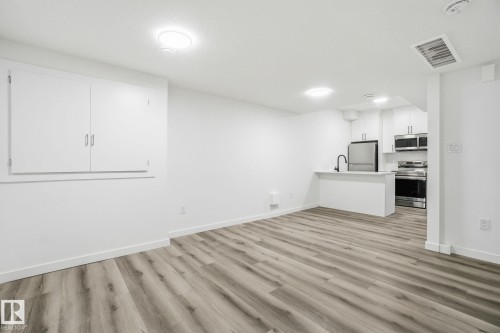 Unfurnished living room featuring light wood finished floors and baseboards - 2532 210 Street, Edmonton, AB - Indoor Photo Showing Kitchen