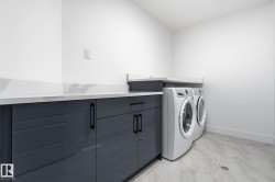 Washroom featuring light marble finish flooring, washer and dryer, and cabinet space - 