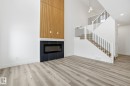 Unfurnished living room featuring a glass covered fireplace, a towering ceiling, wood finished floors, and stairs - 2532 210 Street, Edmonton, AB  - Indoor With Fireplace 