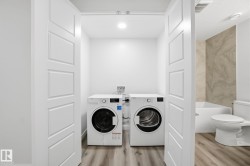 Laundry room with light wood-type flooring and washer and clothes dryer - 
