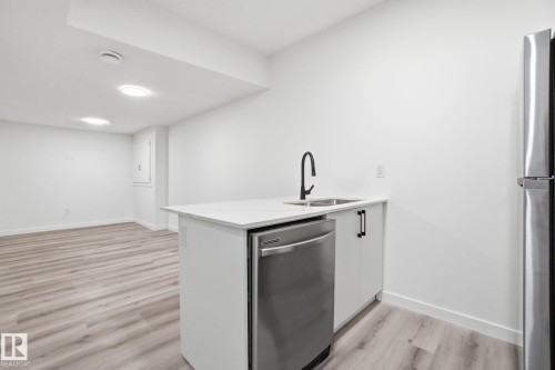 Kitchen with white cabinets, appliances with stainless steel finishes, a peninsula, light wood-type flooring, and light stone countertops - 2532 210 Street, Edmonton, AB - Indoor