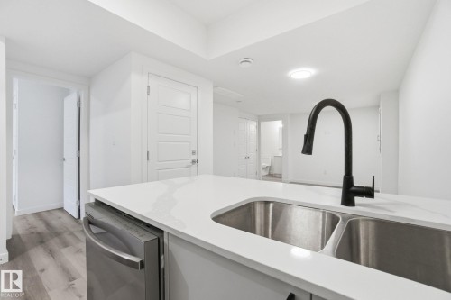 Kitchen with light wood-style flooring, light stone countertops, and stainless steel dishwasher - 2532 210 Street, Edmonton, AB - Indoor Photo Showing Kitchen With Double Sink
