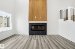 Unfurnished living room with wood finished floors, a high ceiling, stairway, and a glass covered fireplace - 