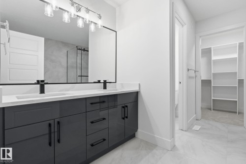 Full bathroom featuring double vanity, a stall shower, light marble finish flooring, and a walk in closet - 2532 210 Street, Edmonton, AB - Indoor Photo Showing Bathroom