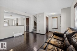 Living room featuring a textured ceiling, dark wood-style flooring, and stairway - 