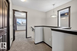 Corridor with an upstairs landing, a textured ceiling, and light carpet - 