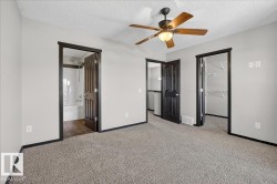 Unfurnished bedroom with a spacious closet, a textured ceiling, carpet flooring, ceiling fan, and connected bathroom - 