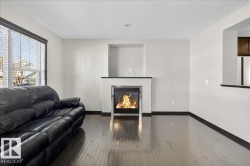 Living area featuring a glass covered fireplace, a textured ceiling, and wood-type flooring - 