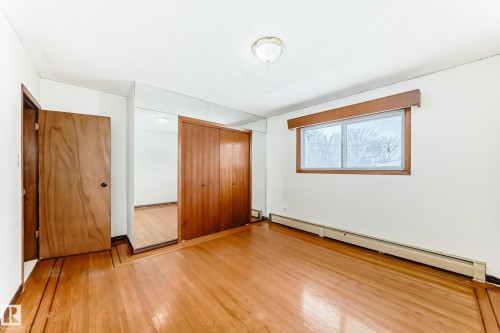 Unfurnished bedroom with a baseboard heating unit, a closet, and wood finished floors - 12028 87 Street, Edmonton, AB - Indoor Photo Showing Other Room