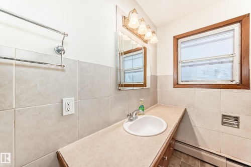 Bathroom featuring baseboard heating, vanity, and tile walls - 12028 87 Street, Edmonton, AB - Indoor Photo Showing Bathroom
