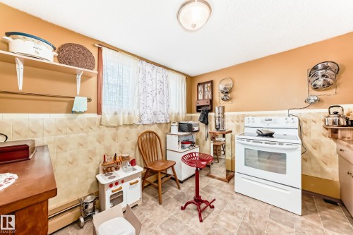 Kitchen featuring white range with electric cooktop, wainscoting, open shelves, tile walls, and a baseboard radiator - 12028 87 Street, Edmonton, AB - Indoor Photo Showing Kitchen