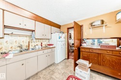 Kitchen featuring freestanding refrigerator, a textured ceiling, white cabinetry, open shelves, and light countertops - 