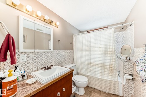Bathroom with shower / tub combo, tile walls, vanity, light tile patterned floors, and wainscoting - 12028 87 Street, Edmonton, AB - Indoor Photo Showing Bathroom