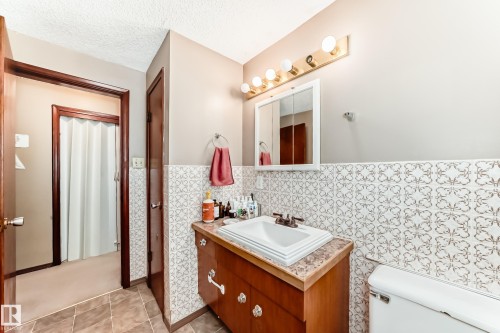 Half bath with vanity, wainscoting, tile walls, a textured ceiling, and light tile patterned floors - 12028 87 Street, Edmonton, AB - Indoor Photo Showing Bathroom