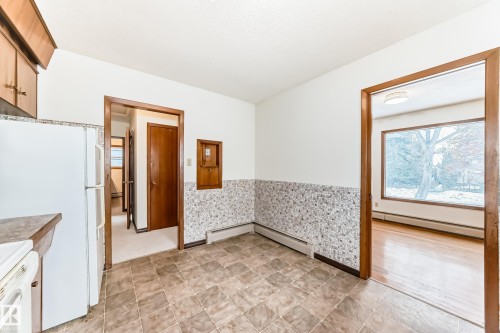 Kitchen featuring a wainscoted wall, a baseboard radiator, and white appliances - 12028 87 Street, Edmonton, AB - Indoor