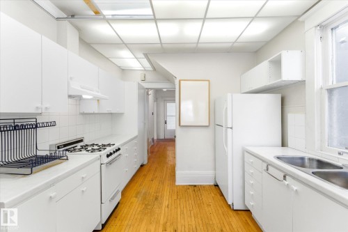 Kitchen with white appliances, white cabinetry, tasteful backsplash, and a drop ceiling - 10921 126 Street, Edmonton, AB - Indoor Photo Showing Kitchen With Double Sink