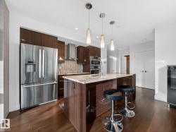 Kitchen with modern cabinets, stainless steel appliances, light stone counters, pendant lighting, and recessed lighting - 