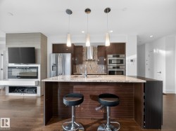 Kitchen featuring dark brown cabinetry, light stone countertops, a kitchen bar, decorative backsplash, and modern cabinets - 