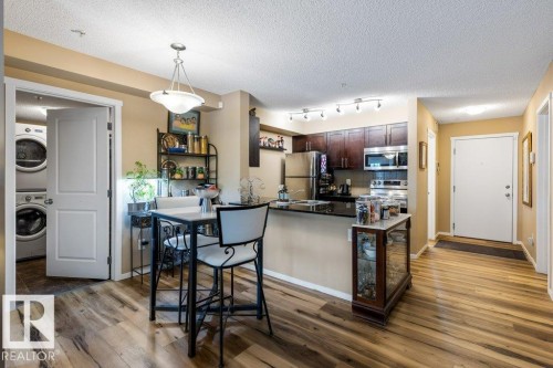 Kitchen with dark brown cabinetry, appliances with stainless steel finishes, hanging light fixtures, a textured ceiling, and dark stone countertops - 107 25 Element Dr, St. Albert, AB - Indoor Photo Showing Kitchen