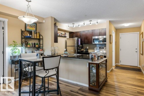 Kitchen with dark brown cabinetry, decorative backsplash, appliances with stainless steel finishes, pendant lighting, and a peninsula - 107 25 Element Dr, St. Albert, AB - Indoor Photo Showing Kitchen