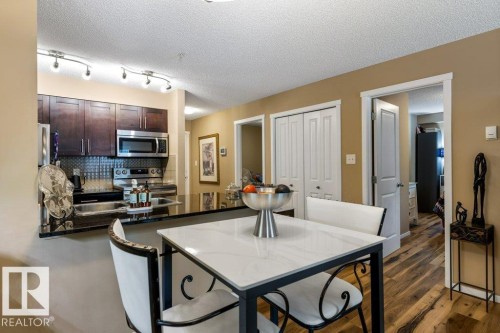 Kitchen with a peninsula, dark brown cabinetry, appliances with stainless steel finishes, tasteful backsplash, and a textured ceiling - 107 25 Element Dr, St. Albert, AB - Indoor