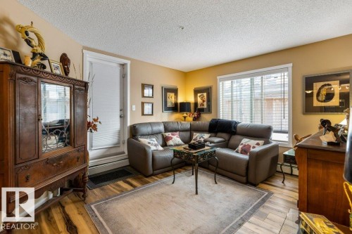 Living area featuring wood-type flooring, a textured ceiling, and a baseboard radiator - 107 25 Element Dr, St. Albert, AB - Indoor Photo Showing Living Room