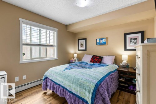 Bedroom with a baseboard radiator, a textured ceiling, and wood finished floors - 107 25 Element Dr, St. Albert, AB - Indoor Photo Showing Bedroom