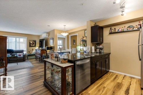 Kitchen featuring dark stone countertops, appliances with stainless steel finishes, light wood-style flooring, open floor plan, and dark brown cabinetry - 107 25 Element Dr, St. Albert, AB - Indoor
