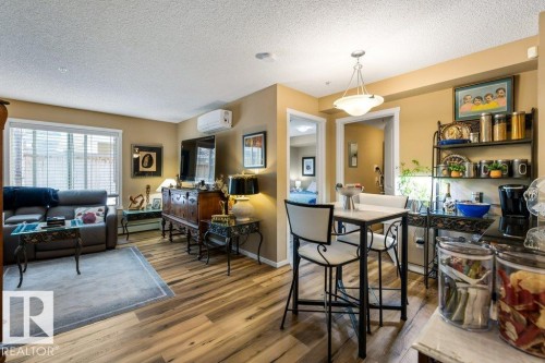 Dining room featuring wood finished floors, a textured ceiling, a baseboard radiator, and a wall mounted air conditioner - 107 25 Element Dr, St. Albert, AB - Indoor Photo Showing Living Room