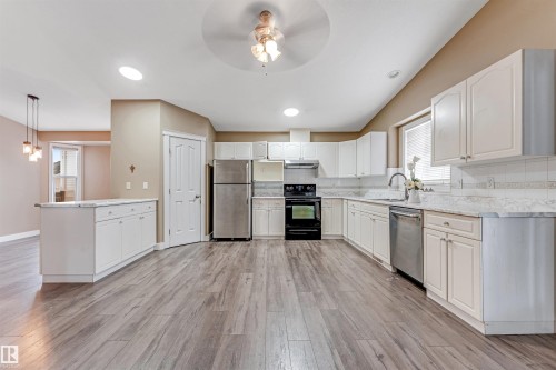 Kitchen with appliances with stainless steel finishes, decorative backsplash, white cabinetry, a peninsula, and a ceiling fan - 6741 162A Avenue, Edmonton, AB - Indoor Photo Showing Kitchen