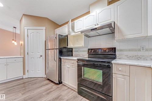 Kitchen featuring black / electric stove, under cabinet range hood, light countertops, and backsplash - 6741 162A Avenue, Edmonton, AB - Indoor Photo Showing Kitchen