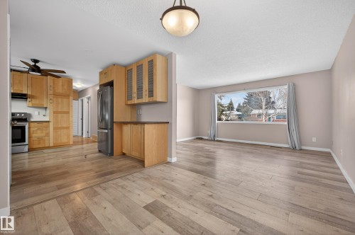 Kitchen featuring stainless steel appliances, light wood-type flooring, a ceiling fan, a textured ceiling, and dark countertops - 8328 164 Street, Edmonton, AB - Indoor Photo Showing Living Room