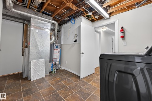 Laundry room featuring water heater, independent washer and dryer, and dark stone finish flooring - 8328 164 Street, Edmonton, AB - Indoor Photo Showing Basement