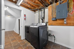 Laundry area with electric panel, washer and dryer, and stone finish flooring - 