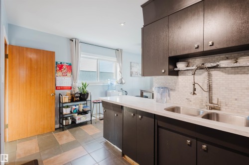 Kitchen featuring decorative backsplash, dark brown cabinets, recessed lighting, and light stone countertops - 13315 134 Avenue, Edmonton, AB - Indoor Photo Showing Kitchen With Double Sink