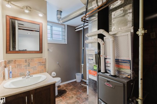 Bathroom featuring vanity, heating unit, and decorative backsplash - 13315 134 Avenue, Edmonton, AB - Indoor