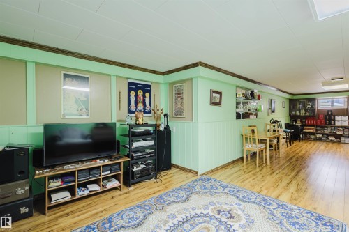 Living room featuring light wood-style flooring, crown molding, and a wainscoted wall - 13315 134 Avenue, Edmonton, AB - Indoor