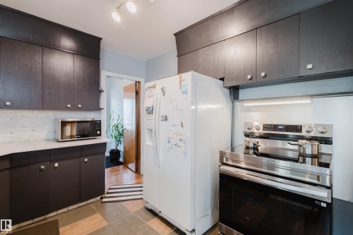 Kitchen featuring appliances with stainless steel finishes, dark brown cabinetry, and backsplash - 13315 134 Avenue, Edmonton, AB - Indoor Photo Showing Kitchen