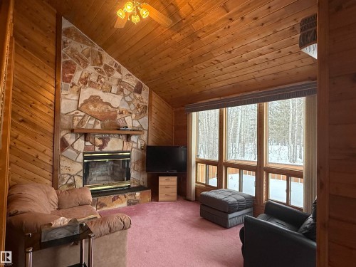 Carpeted living area with a fireplace, wood walls, wood ceiling, high vaulted ceiling, and a ceiling fan - 34 Ella Mae Crescent, Athabasca Town, AB - Indoor Photo Showing Living Room With Fireplace