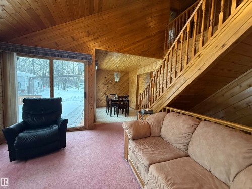 Carpeted living area featuring stairs, wood walls, a high ceiling, and wood ceiling - 34 Ella Mae Crescent, Athabasca Town, AB - Indoor Photo Showing Other Room