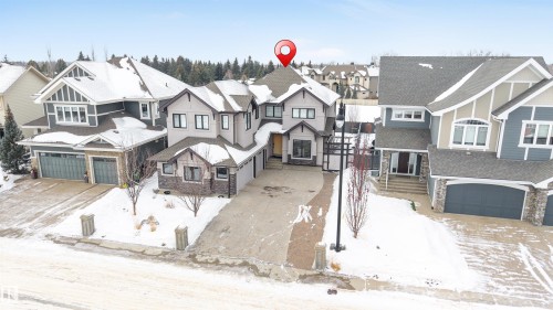 View of front facade featuring stone siding, a residential view, a garage, and driveway - 656 180 Street, Edmonton, AB - Outdoor With Facade
