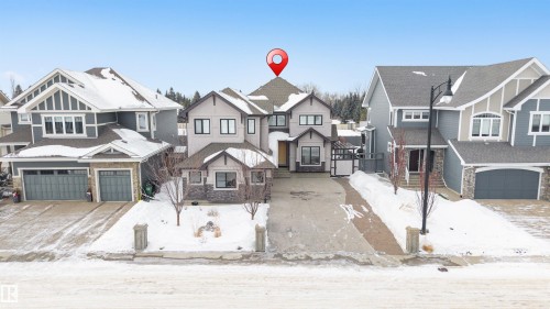 View of front facade featuring stone siding, a residential view, an attached garage, and concrete driveway - 656 180 Street, Edmonton, AB - Outdoor With Facade