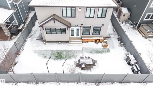 Snow covered property with a fenced backyard, stucco siding, a patio area, roof with shingles, and french doors - 656 180 Street, Edmonton, AB - Outdoor