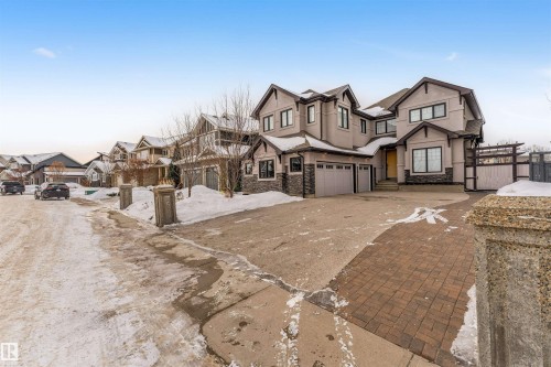 View of front facade featuring a residential view, stone siding, stucco siding, concrete driveway, and an attached garage - 656 180 Street, Edmonton, AB - Outdoor With Facade