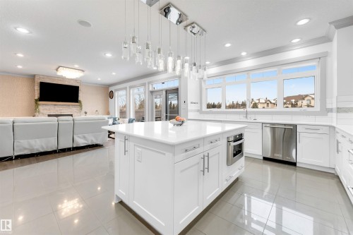 Kitchen featuring open floor plan, ornamental molding, white cabinets, decorative light fixtures, and a center island - 656 180 Street, Edmonton, AB - Indoor Photo Showing Kitchen With Upgraded Kitchen