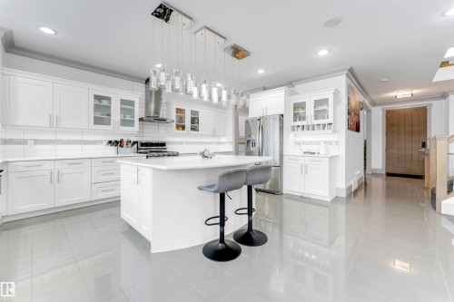 Kitchen featuring glass insert cabinets, a kitchen bar, a center island, decorative backsplash, and white cabinets - 656 180 Street, Edmonton, AB - Indoor Photo Showing Kitchen With Upgraded Kitchen