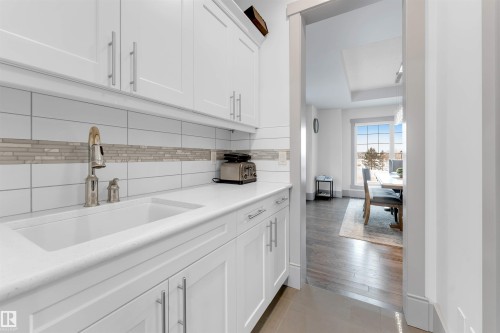 Kitchen with white cabinets, dark tile patterned floors, a raised ceiling, and decorative backsplash - 656 180 Street, Edmonton, AB - Indoor Photo Showing Kitchen