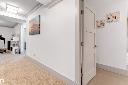 Hallway featuring a textured ceiling, crown molding, and light tile patterned floors - 656 180 Street, Edmonton, AB - Indoor Photo Showing Other Room